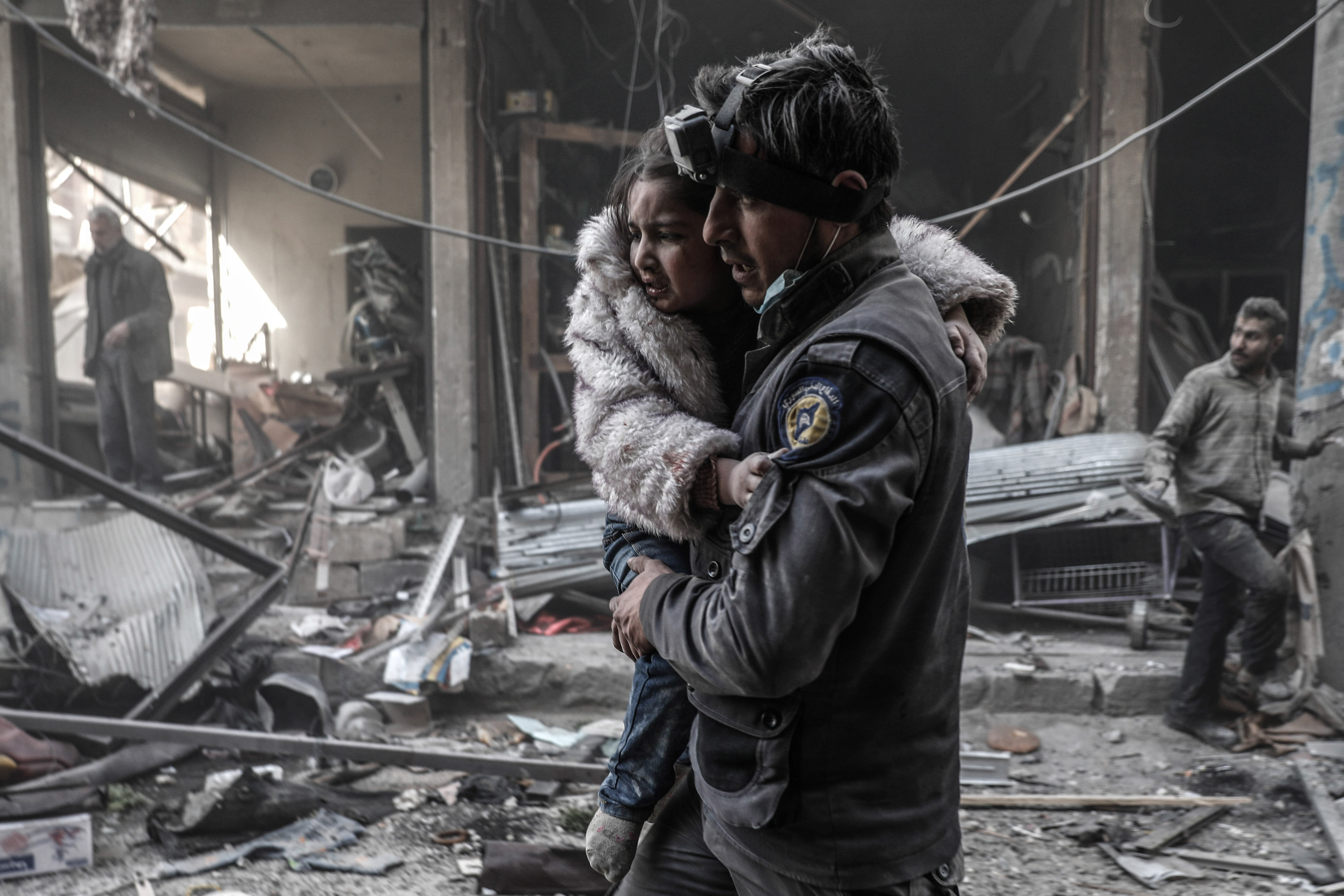 A member of the Syrian Civil Defence volunteers, also known as the White Helmets, carries a wounded girl amid the rubble following reported government airstrike on the rebel-held town of Douma, on the eastern outskirts of the capital Damascus, on February 25, 2017.
Syrian regime forces carried out raids on several areas in the country, targeting mainly the besieged town of Douma, causing the deaths of at least 13 civilians, according to Syrian Observatory for Human Rights. The raids continued despite the United Nations confirmation a few days earlier that Moscow formally asked its ally Damascus to stop launching strikes during the Geneva negotiations, which began earlier in the week. / AFP PHOTO / Sameer Al-Doumy